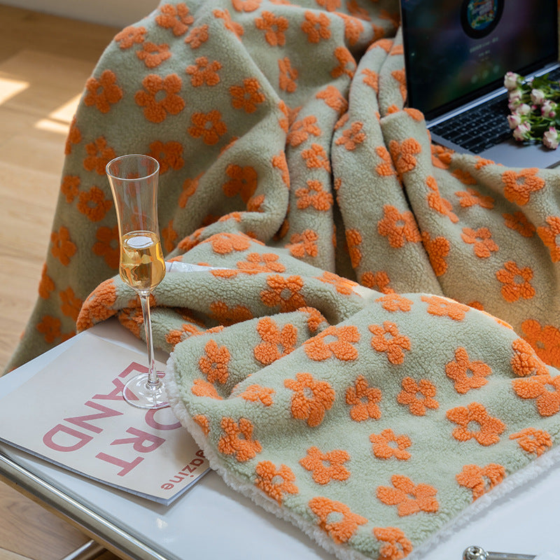 Floral jacquard sherpa-back throw blanket in sage with orange flowers, draped over a lap, shown in use with a laptop and