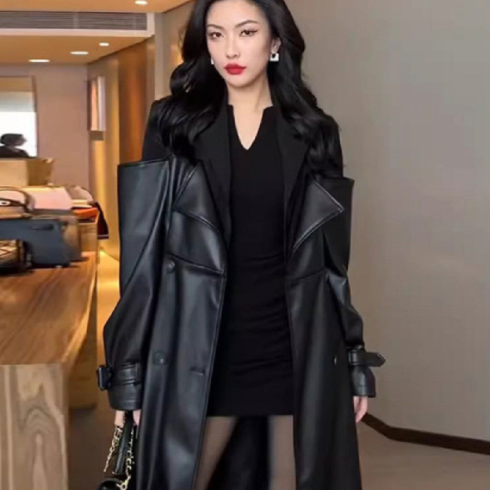 Long black trench coat with contrast shoulders, double-breasted, wide lapels, waist belt and buckled cuffs, worn by a model