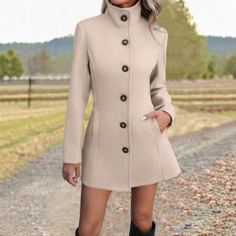 Fitted stand-collar coat in apricot, single-breasted with button front, worn by model on gravel path