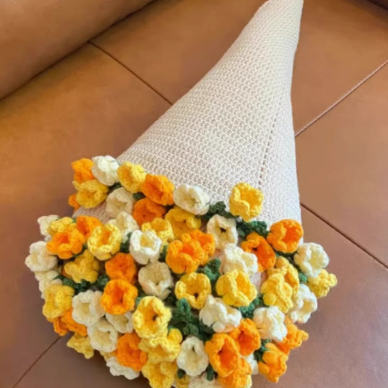 Crochet flower bouquet blanket with yellow and white flowers, folded into a bouquet shape, lying on a brown surface
