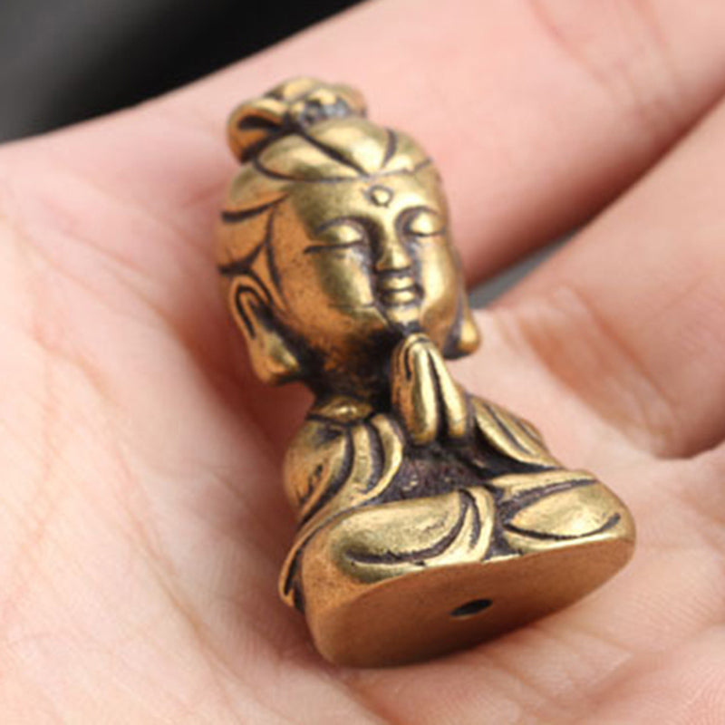 Small brass-look meditating figure ornament held in hand, side view showing size and details