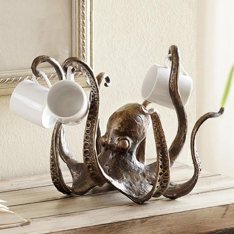 Bronze-look resin octopus cup holder with small white cups, front view on a wooden shelf
