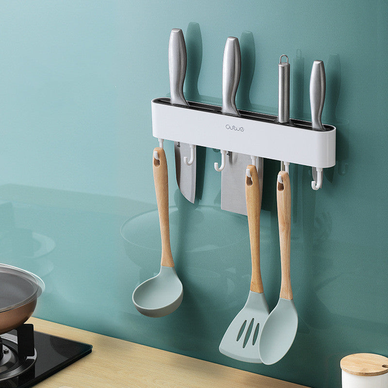 Wall-mounted magnetic knife bar with hooks, white, holding knives and utensils, angled view in kitchen setting