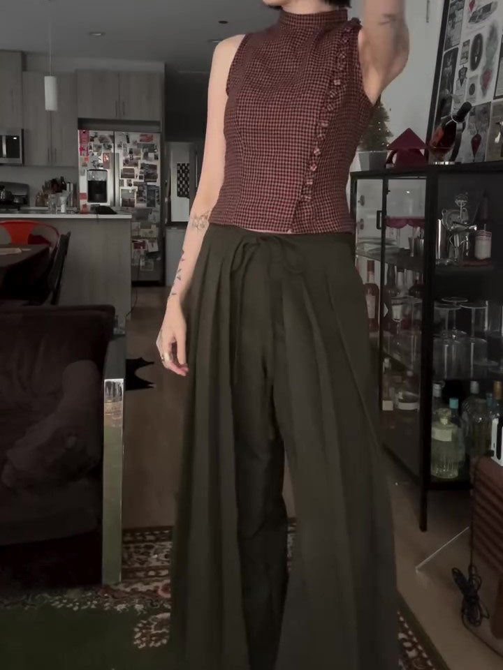 Olive wide-leg trousers with tie waist, side view on model adjusting top in living space
