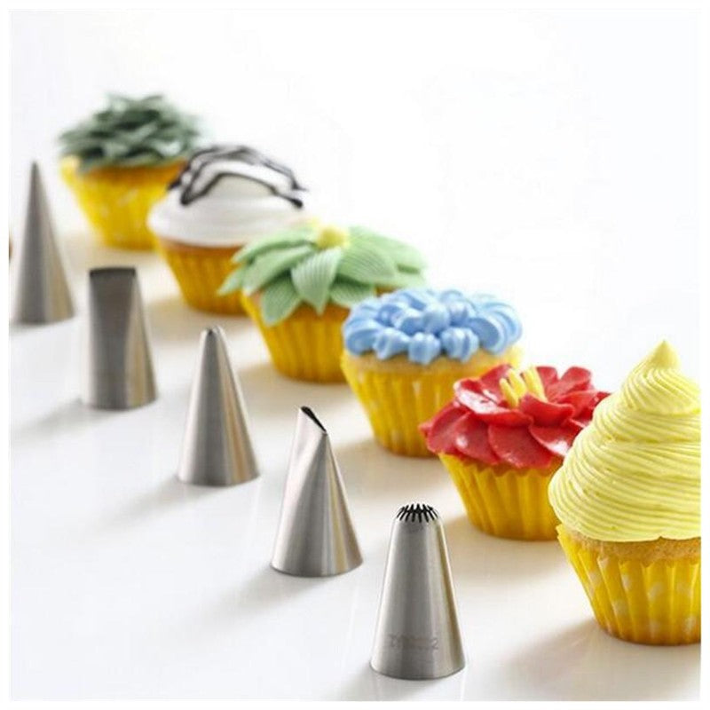 Stainless steel piping nozzles in a row with cupcakes decorated using different floral and textured icing designs
