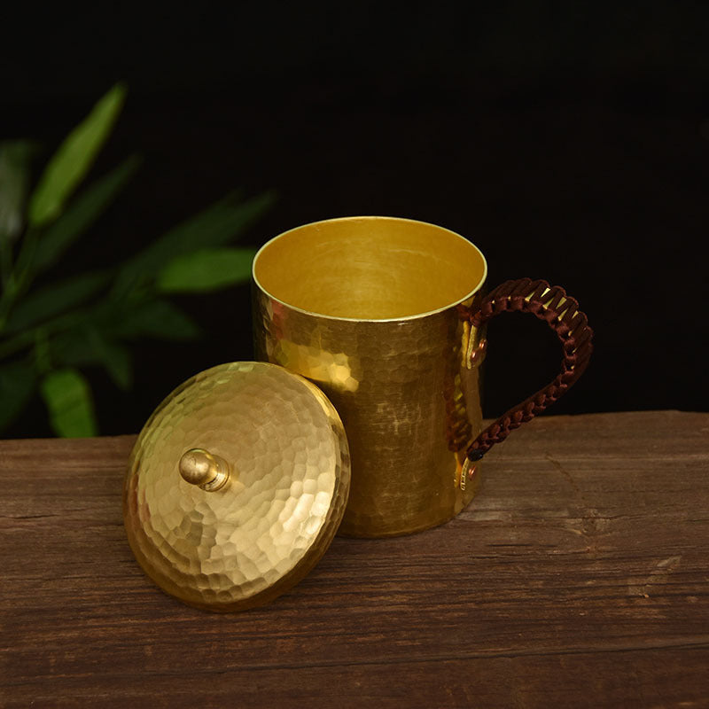 Hammered brass mug with lid off, showing interior, side view on wooden surface