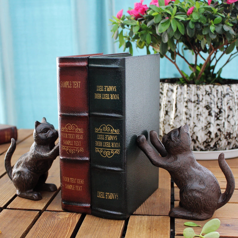 Cast-iron cat bookends, dark brown, holding books upright on wooden surface, front view, in use