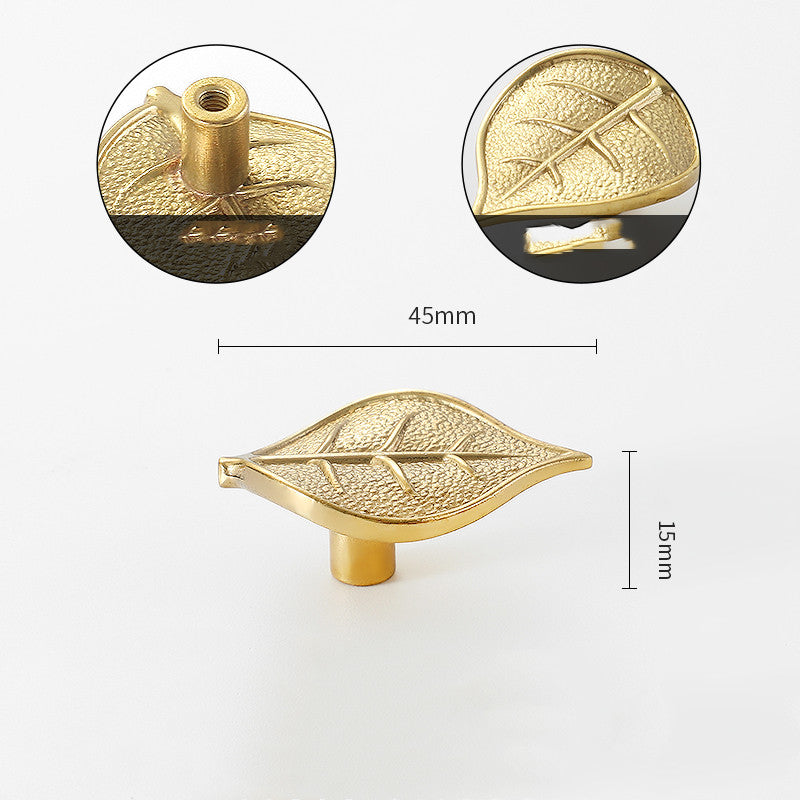 Gold-tone leaf-shaped cabinet knob, front view with detail of stem and texture, flat lay on white background