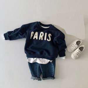 Marineblauwe PARIS-trui over een wit T-shirt met sneakers