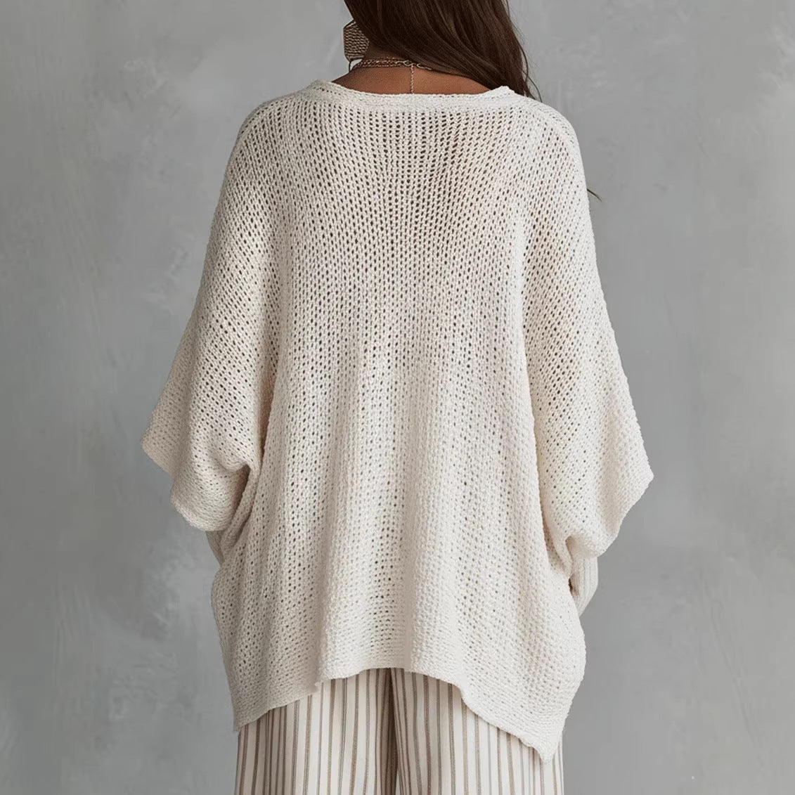 Oversized open-knit top in white, back view on model, dolman sleeves, dropped shoulder, asymmetric hem
