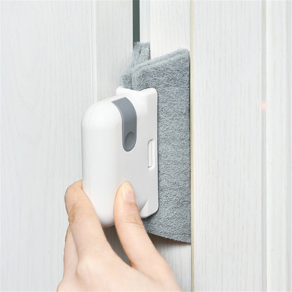 White cleaning brush with grey pad being used to clean a narrow vertical gap between panels