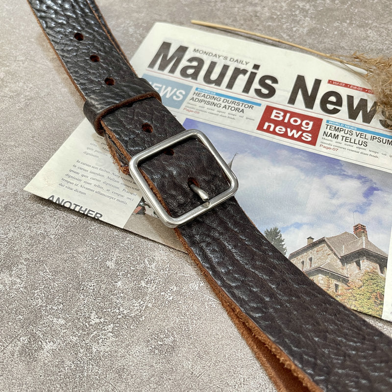 Leather belt dark brown, silver-tone buckle, textured surface, on newspaper