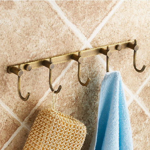 5-hook wall rail in antique brass-tone finish, mounted on tiled wall, with blue towel and loofah hanging