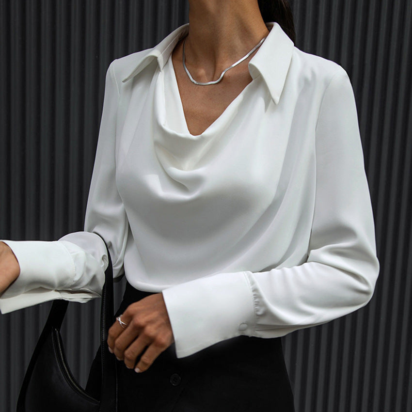 Cowl-neck collared satin-look blouse in white, front view on model, paired with black skirt and bag, against dark striped