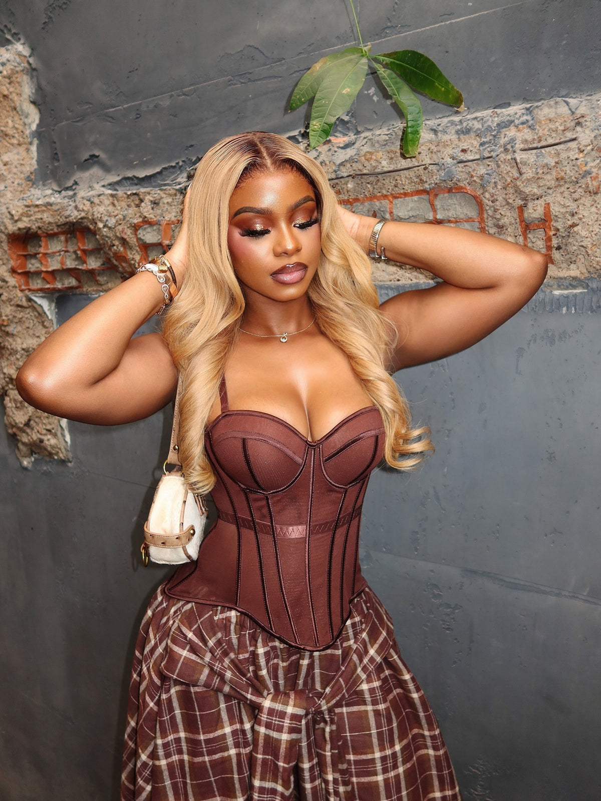 Boned corset top and asymmetric plaid skirt co-ord set in brown and beige, worn by model from front, hands on hair, against