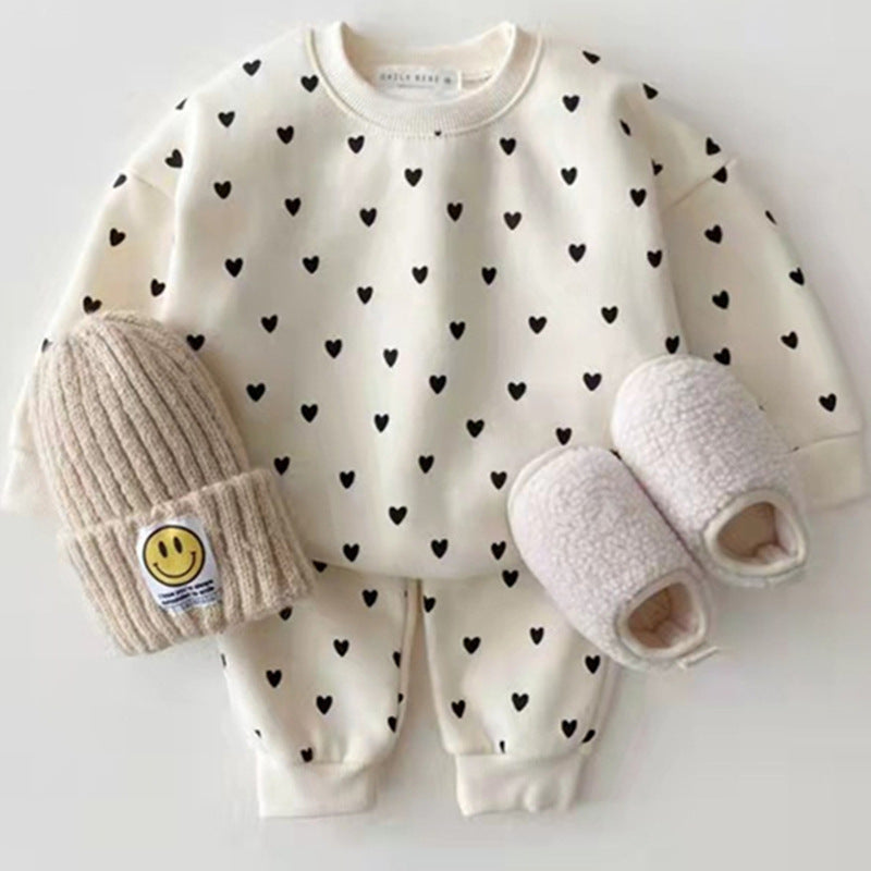 Cream sweatshirt and trousers set with black hearts, beanie and slippers beside it