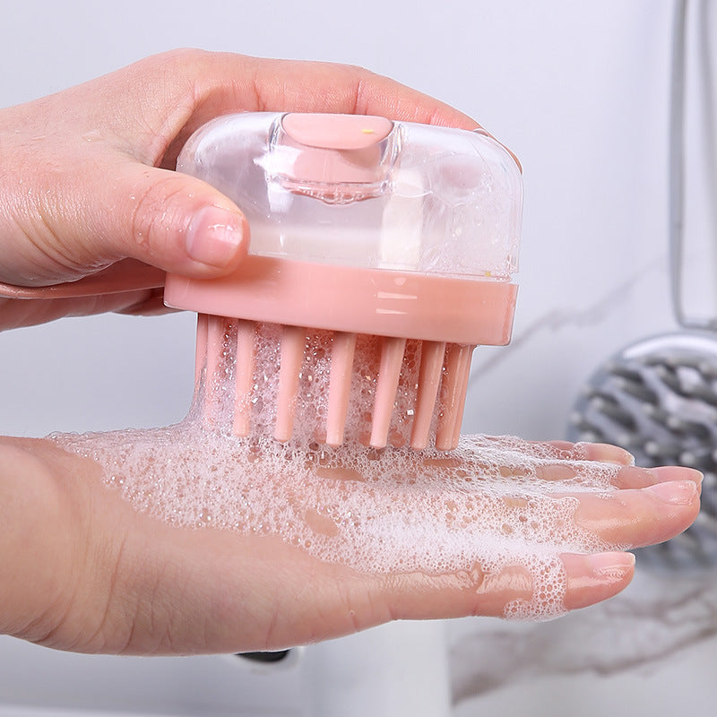 Pink shampoo brush with clear dome, pressing shampoo foam onto the palm of a hand