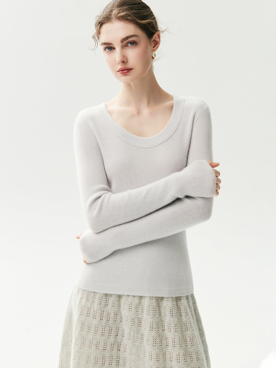 Lichtgrijze geribde cashmere trui met U-hals op een model met gekruiste armen, vooraanzicht