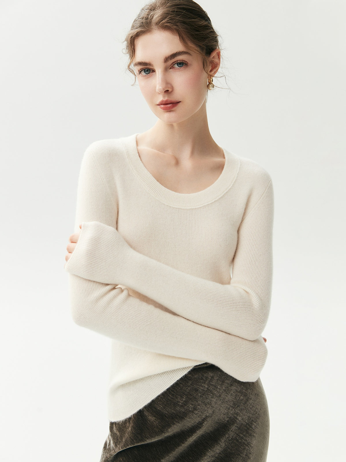 Cream geribde cashmere trui met U-hals op een model met gekruiste armen, vooraanzicht