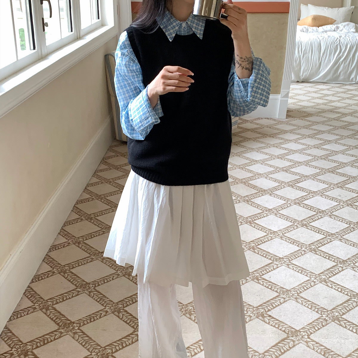 Zwarte wollen cashmere gilet over een blauw geruit overhemd en witte rok
