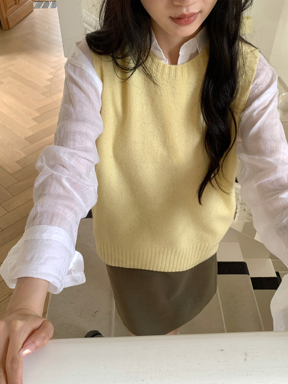 Pale yellow round-neck knit vest layered over a white long-sleeve shirt