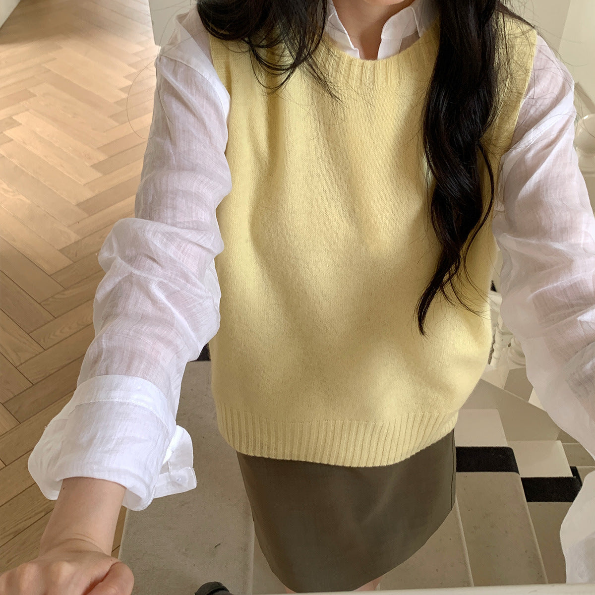 Lichtgele wollen cashmere gilet, close-up van de voorkant over een wit overhemd