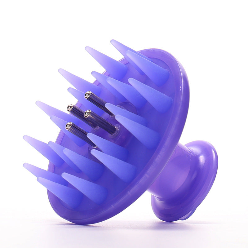 Lavender scalp brush with oil reservoir, angled view showing flexible teeth and central metal pins