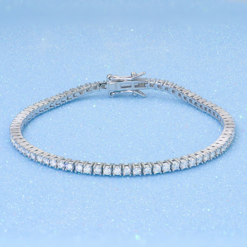 Gesloten zilverkleurige tennis armband met doorlopende rij van 2 mm heldere steentjes op een lichtblauwe achtergrond