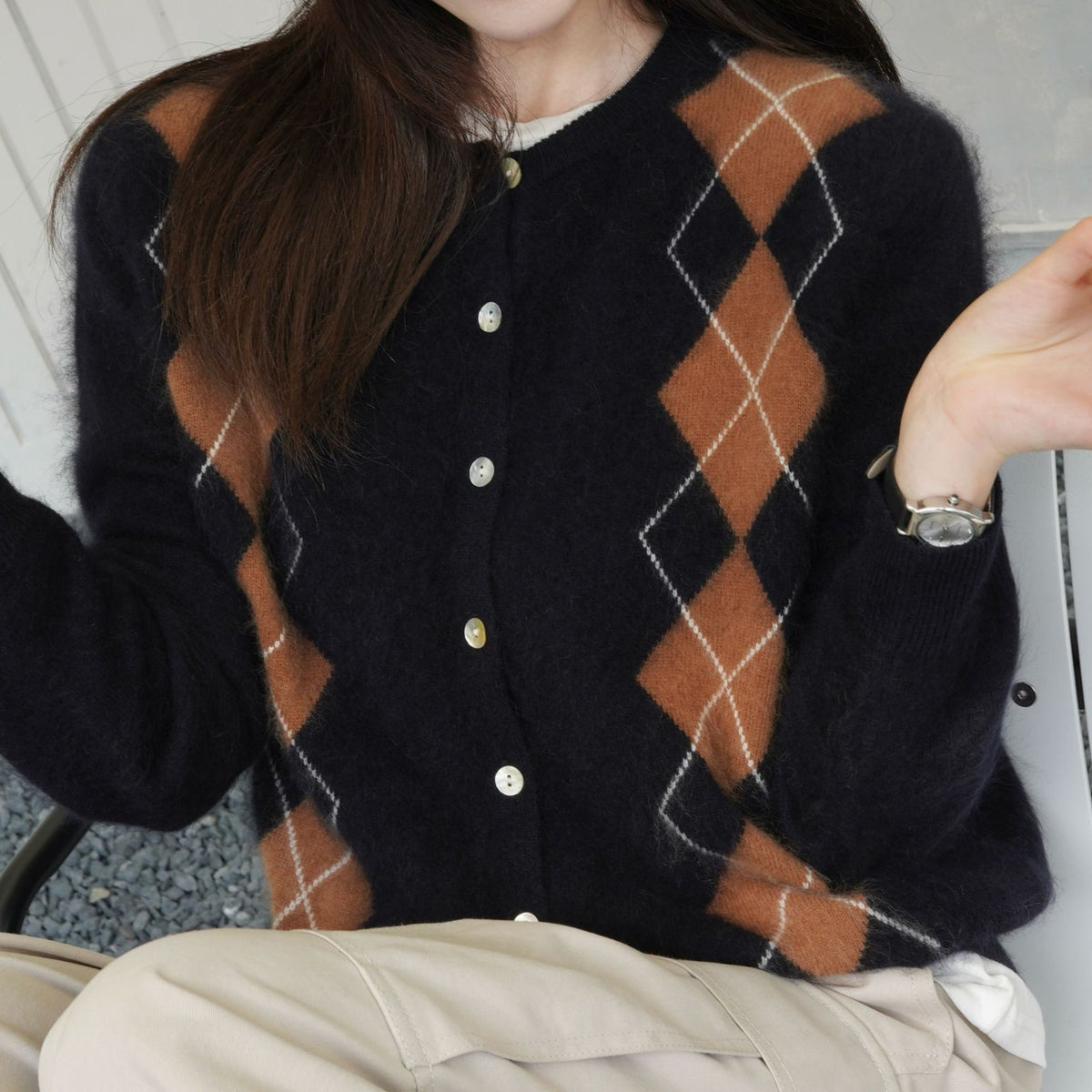 Kleur bruin: close-up van het zwarte vest met bruin en wit argyle patroon en ronde knopen