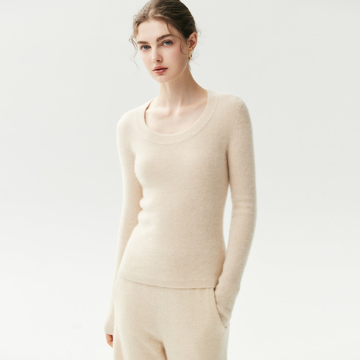 Beige geribde cashmere trui met U-hals op een model, vooraanzicht op driekwart met bijpassende broek