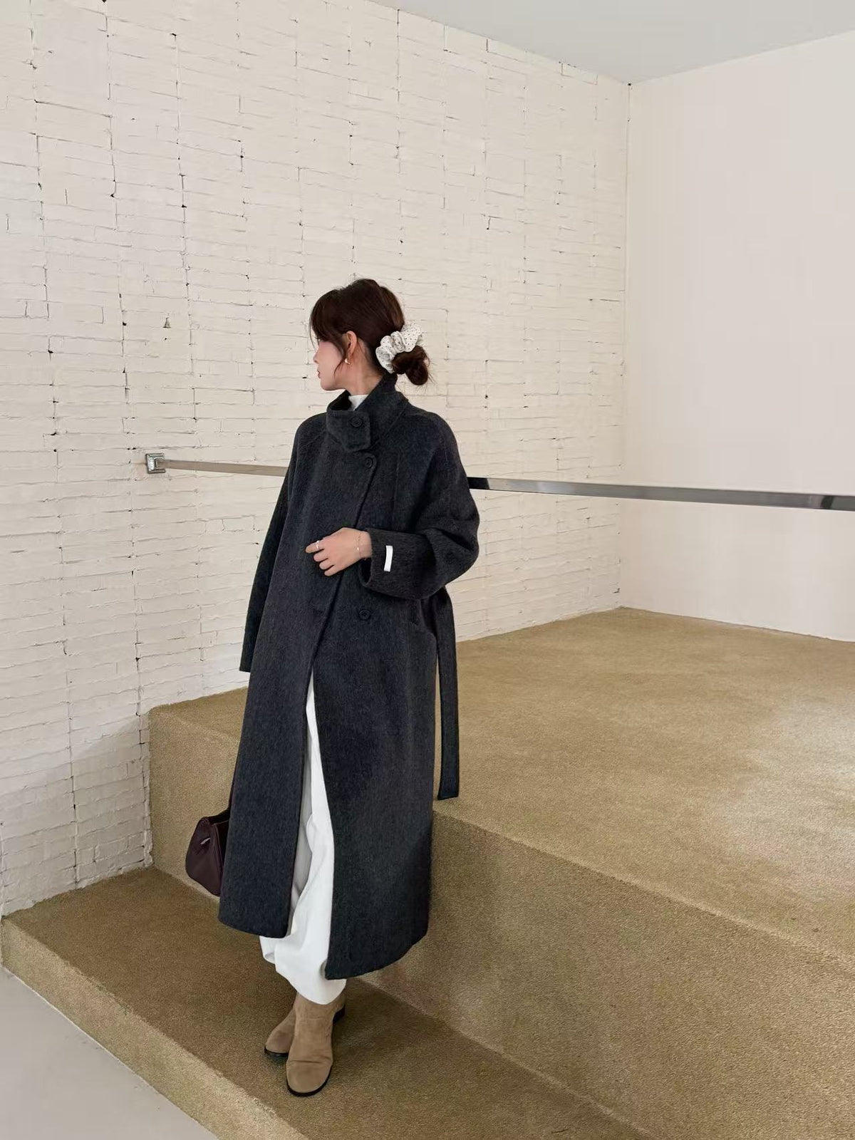 Charcoal grey double-faced wool coat, side view on model standing on concrete steps