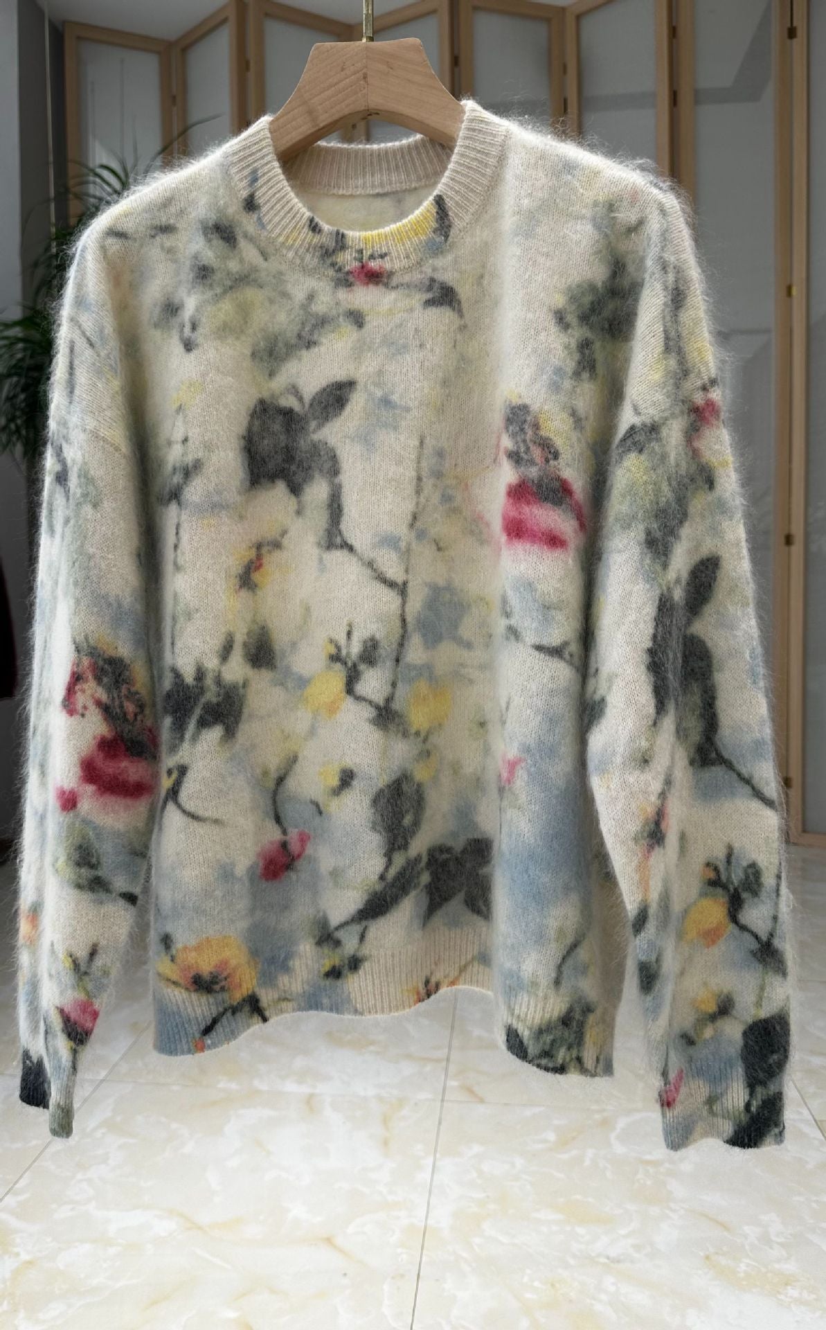 Geborstelde wollen trui met de print inkt bloemen in meerdere kleuren op een crèmekleurige basis, aan een hanger