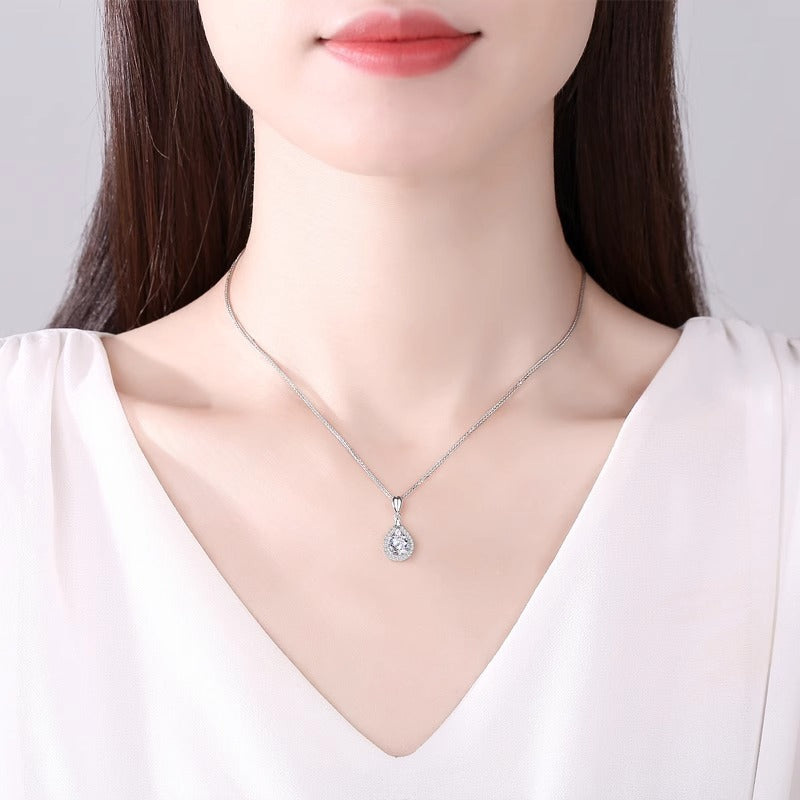 Teardrop pendant necklace worn on a model in a white V-neck top, pendant sitting at the collarbone