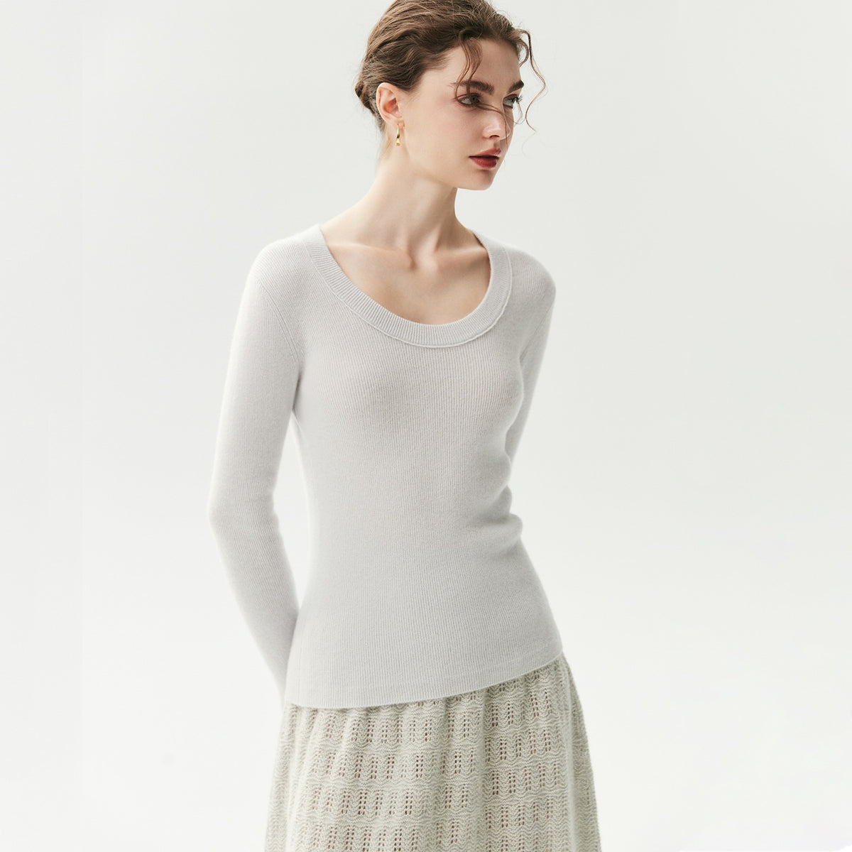 Grijsblauwe geribde cashmere trui met U-hals op een model, vooraanzicht met patroonrok