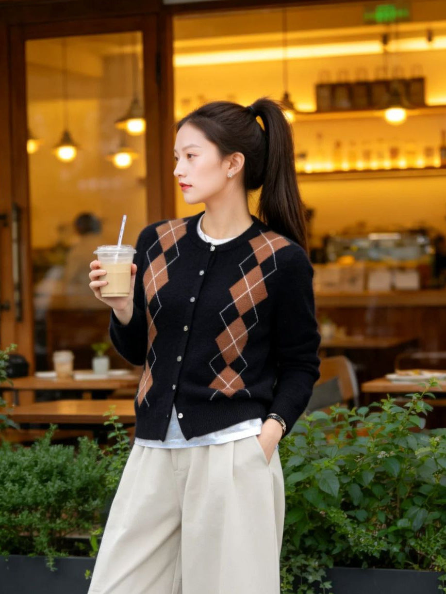 Kleur bruin: zwart argyle vest met karamelbruine ruiten, gedragen met een crèmekleurige broek, met een drankje in de hand