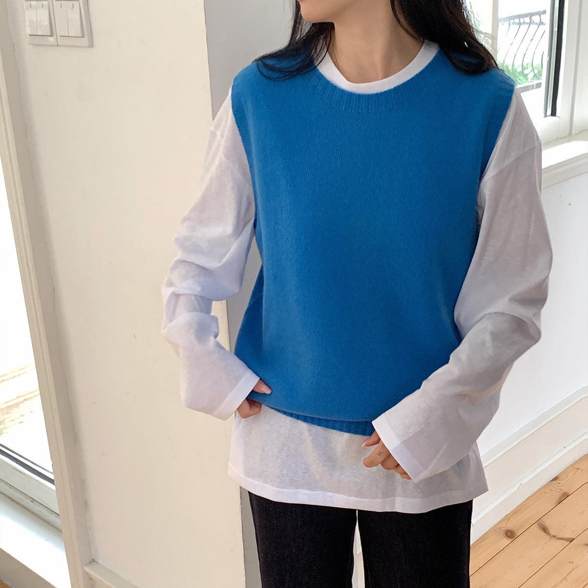 Heldere pauwblauwe wollen gebreide gilet met cashmere over een witte top met lange mouwen