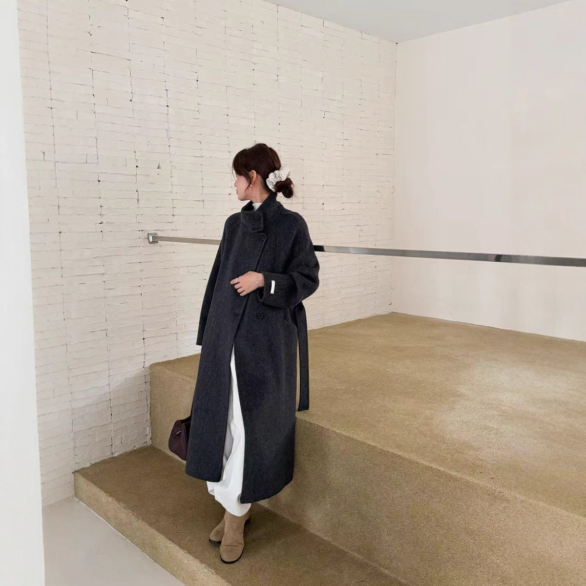 Charcoal grey wool coat, back three-quarter view on model standing on steps