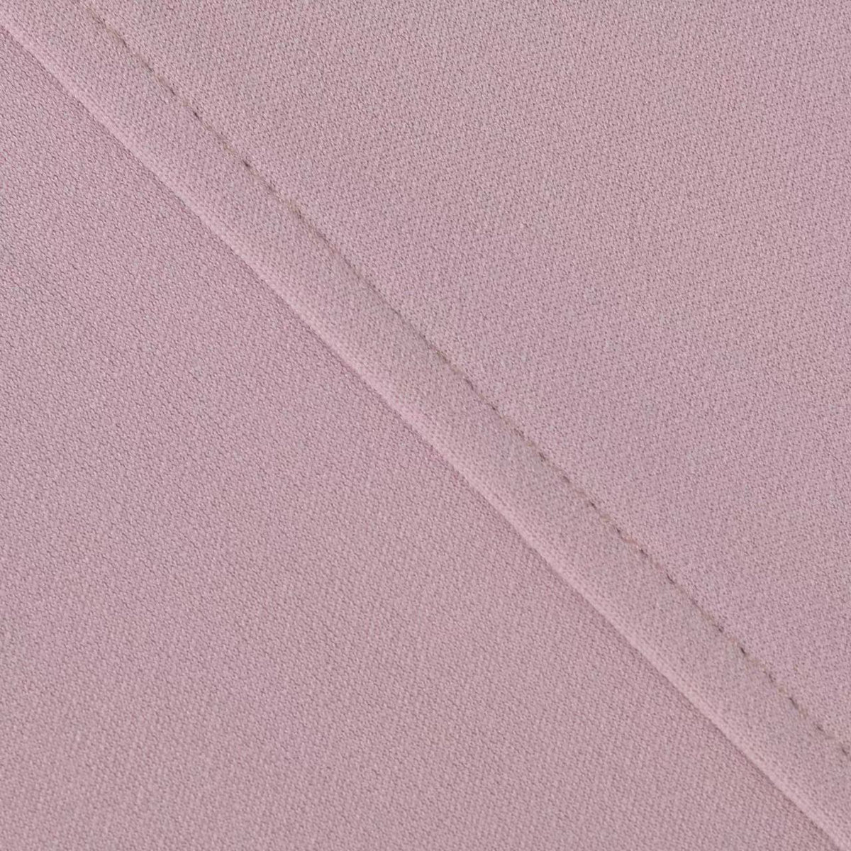 Close-up of fabric texture and seam on dusty pink trousers