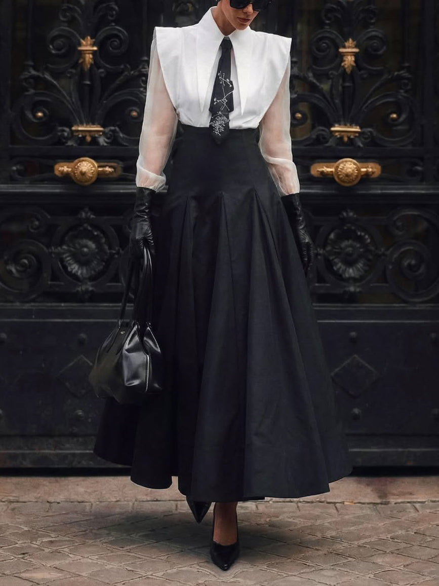 Model wearing the white sheer-sleeve shirt and black maxi skirt set, full front view, styled with tie, gloves and bag