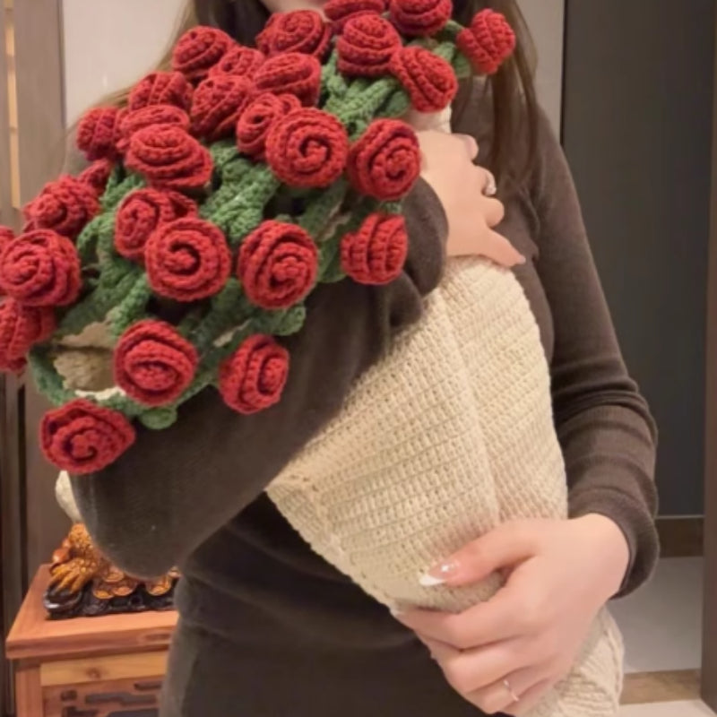 Crochet flower bouquet blanket in red roses, folded into a bouquet shape, held by a person wearing a dark top, indoors