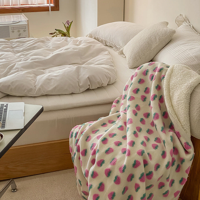 Double-Layer Tufted Flower Blanket with strawberry pattern draped over a bed next to a laptop and a small table
