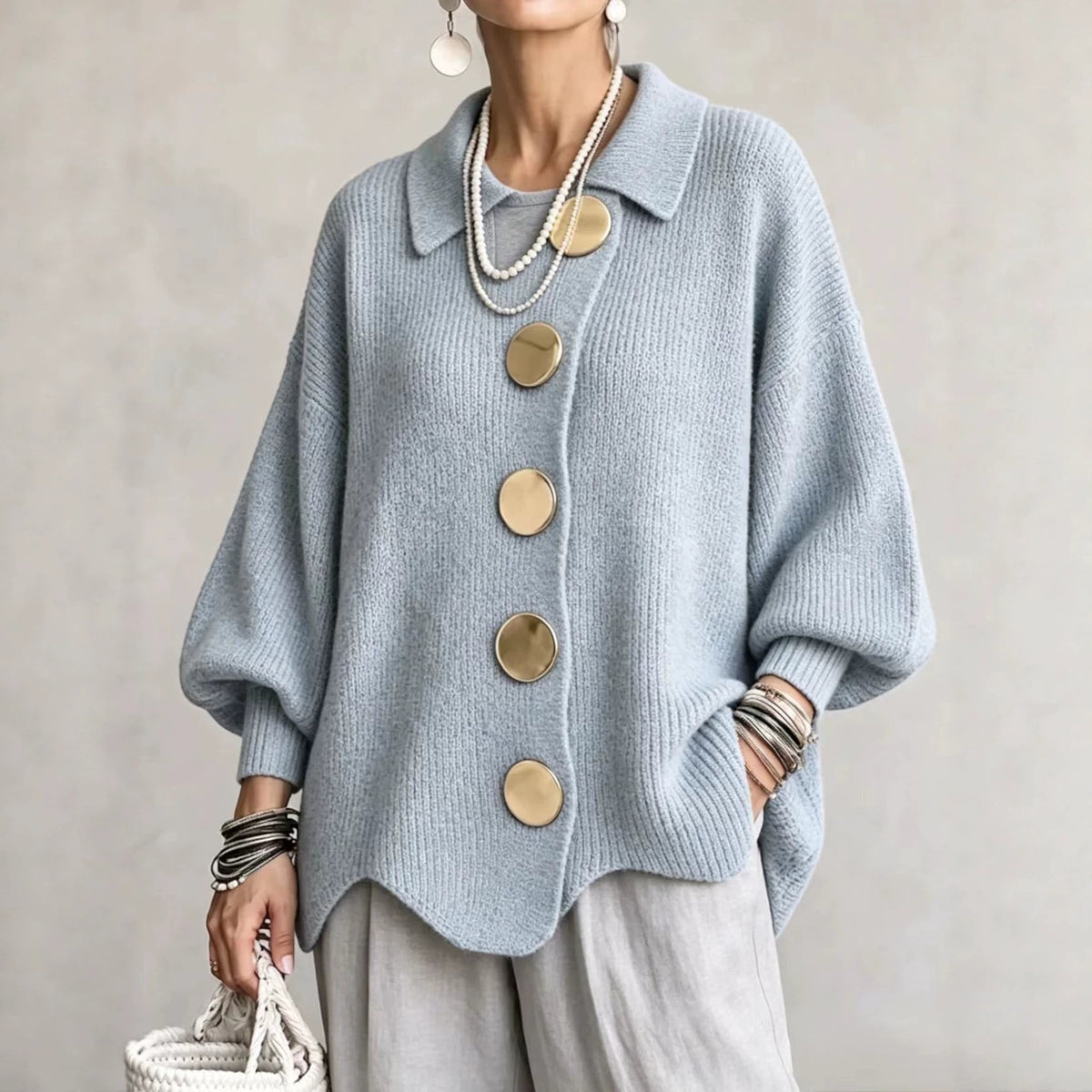 Collared knit cardigan in light blue with large gold buttons, worn on a model, front view, wavy hem, dropped shoulders