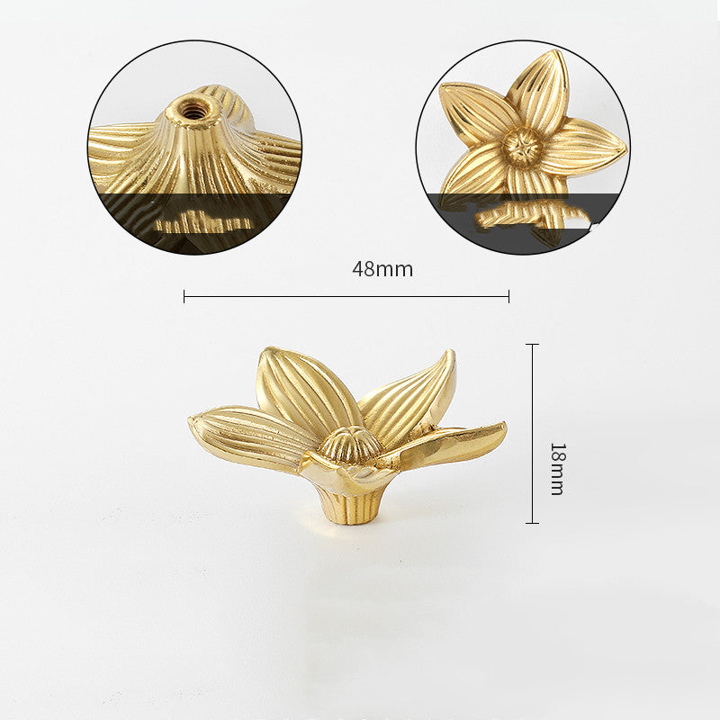 Gold-tone flower-shaped cabinet knob, front view with detail of petals and base, flat lay on white background