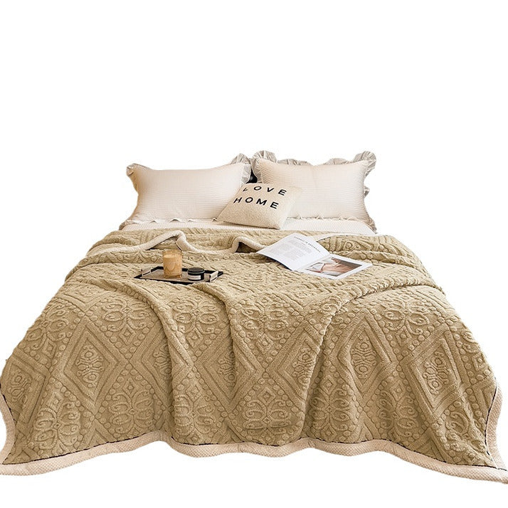 Embossed diamond-pattern velvet-look blanket in beige, flat lay on a bed with pillows and accessories, full view of design