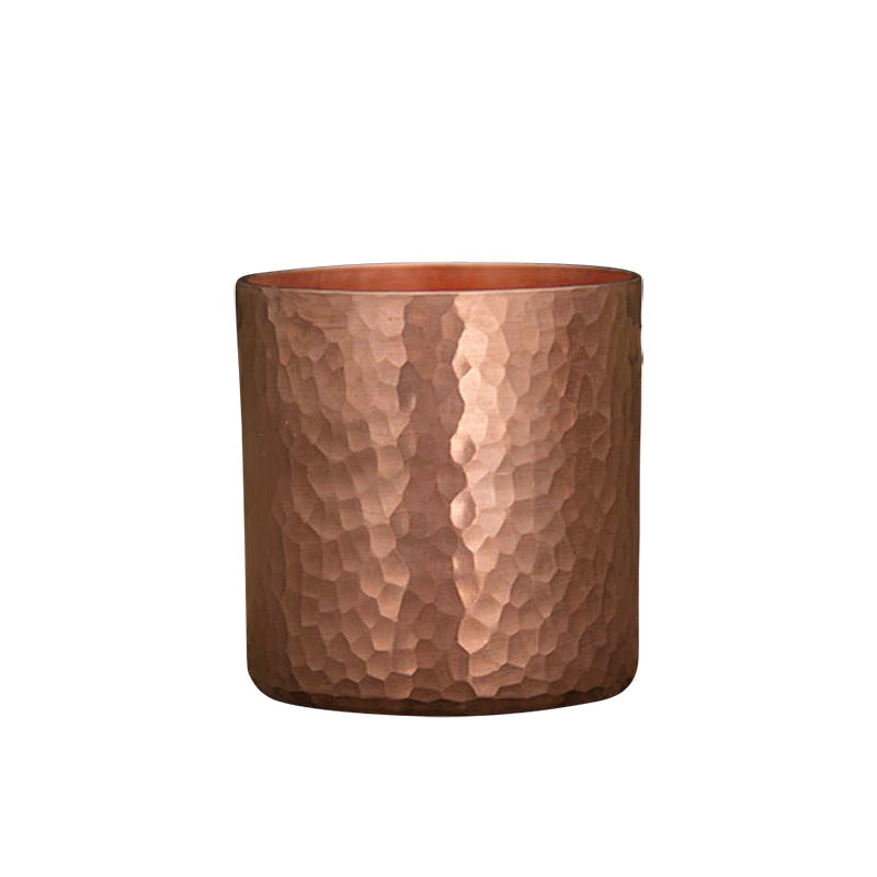 Single hammered metal tea cup, copper colour, front view against white background