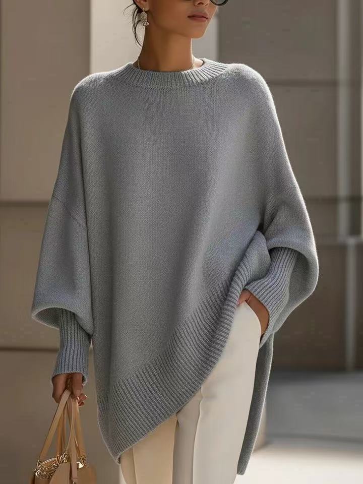 Light grey asymmetric sweater with batwing sleeves over cream trousers