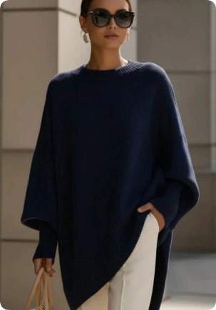 Navy blue asymmetric sweater worn with sunglasses and cream trousers