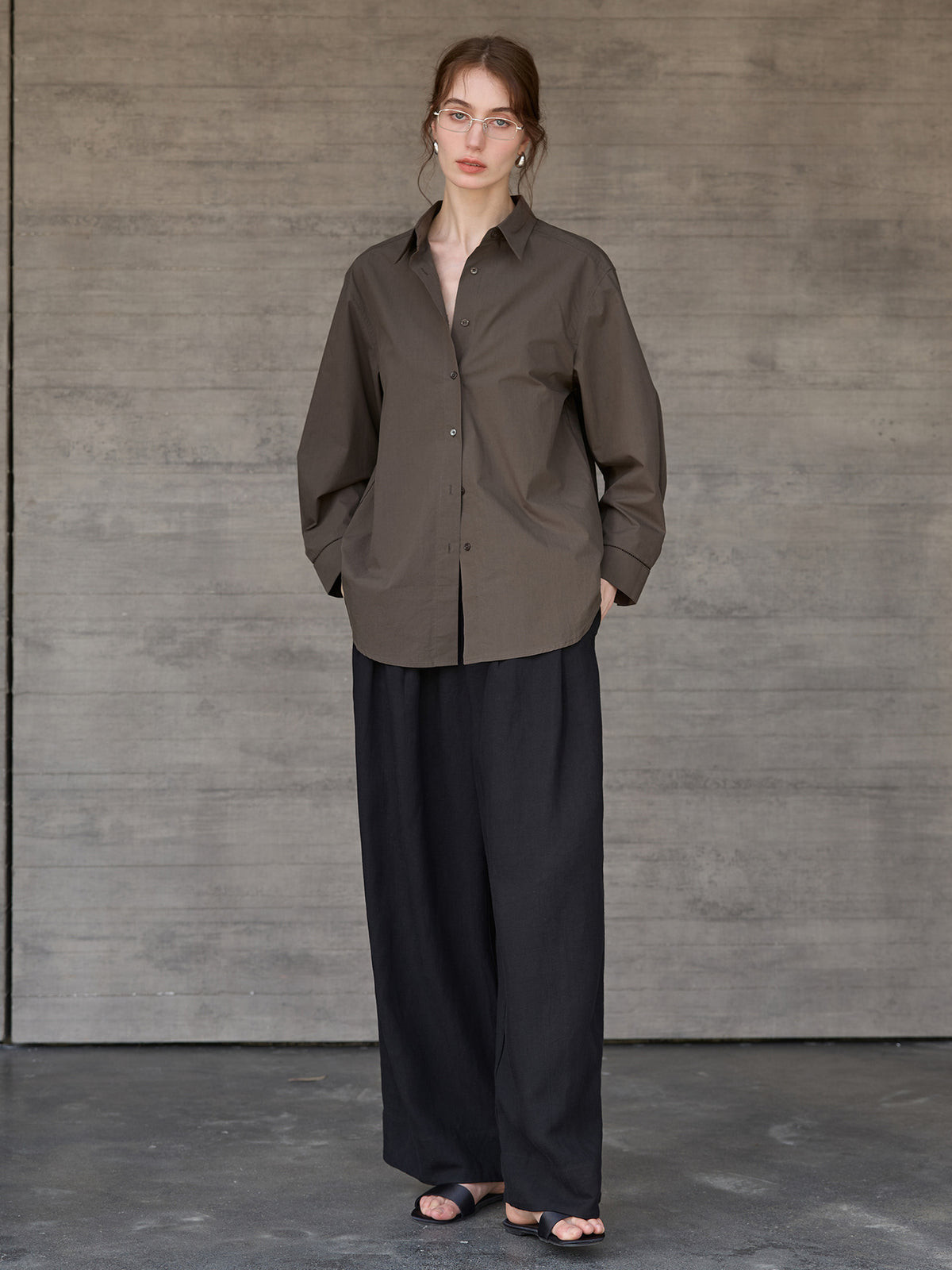 Relaxed long-sleeve shirt with dropped shoulder in dark brown, worn by a model, full body front view, paired with wide pants