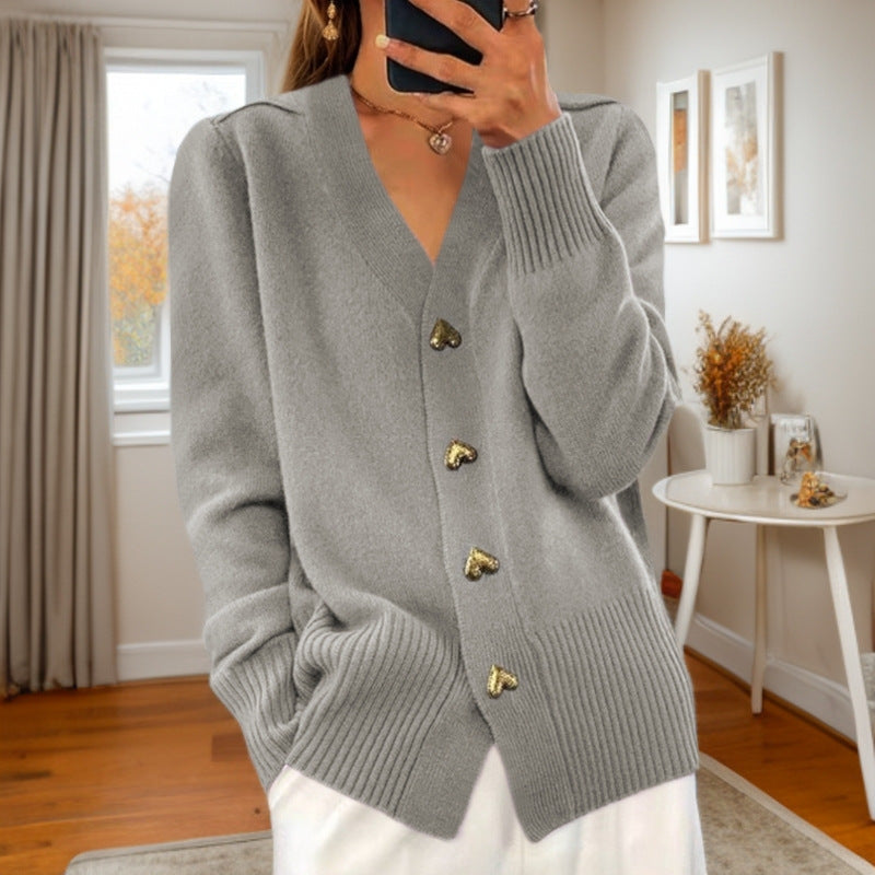 V-neck knit cardigan in grey with heart-shaped buttons, worn by a model in a bright room