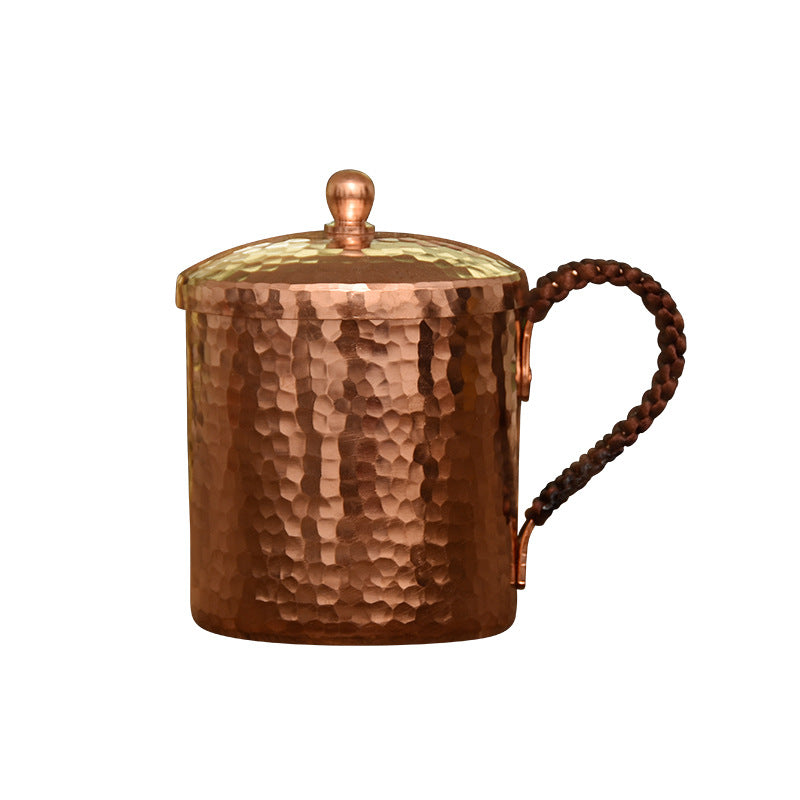 Hammered copper mug with braided handle and domed lid, isolated on white background